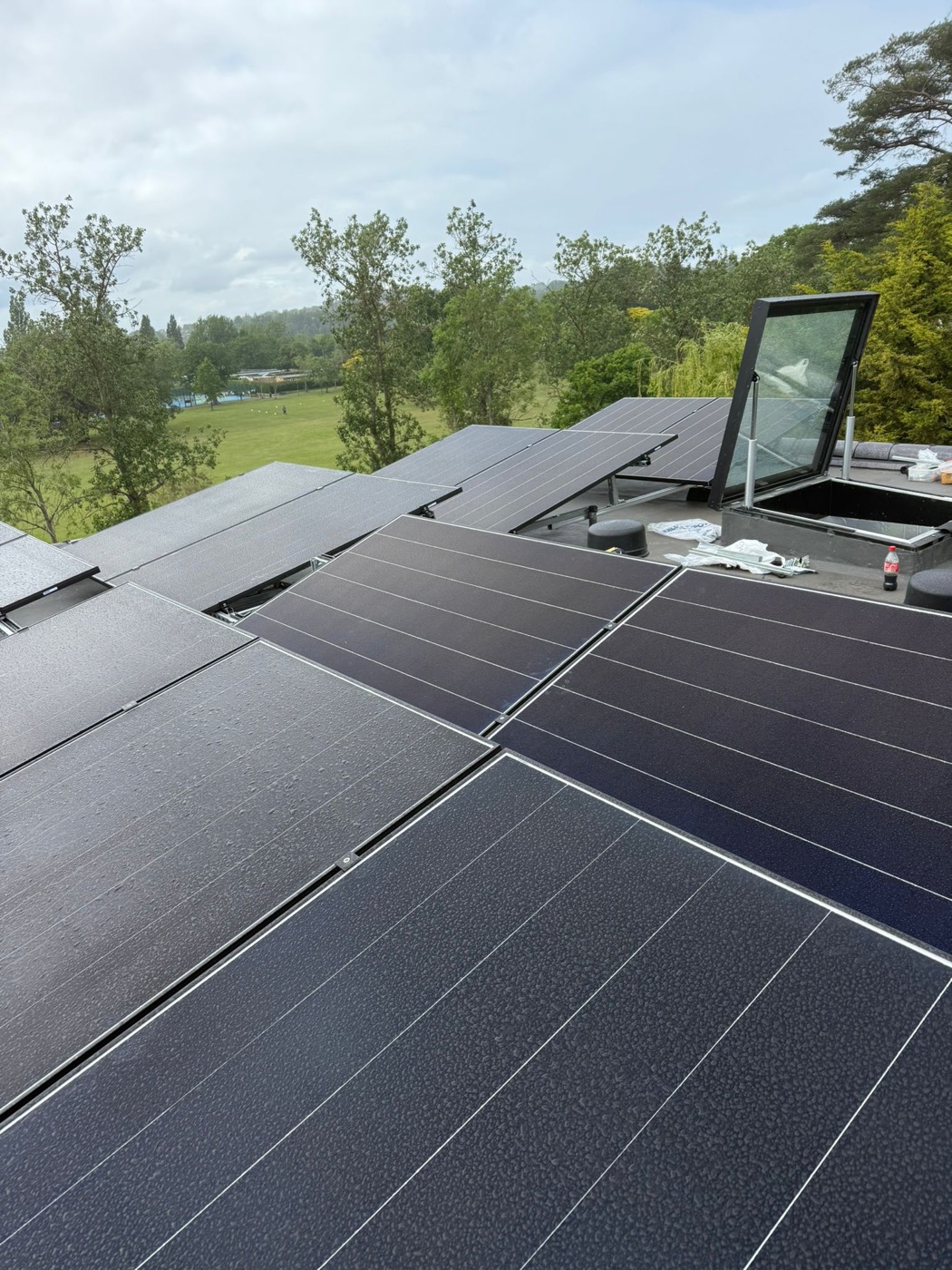 Completed all-black solar array fitted around a roof window, countryside behind